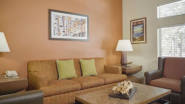 A hotel room with a brown sofa, a coffee table with a decorative item, two lamps, and framed pictures on the wall. - 2-Bedroom South Tahoe Resort Next to Beach & Zephyr Cove - AC & fitness room (Zephyr Cove)