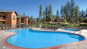 A pool area with lounge chairs, a pool, and wooden cabins in the background. - 2-Bedroom South Tahoe Resort Next to Beach & Zephyr Cove - AC & fitness room (Zephyr Cove)