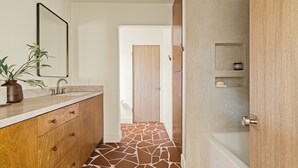 Ein Badezimmer mit einem Holzkosmetikschrank, einem Spiegel, einem Waschbecken und einer Duschkabine.