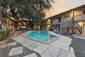 A hotel with a swimming pool, outdoor seating, and a staircase leading to the upper floors. - Gated Austin 2BR Condo+ Pool - Near South Congress (Austin)