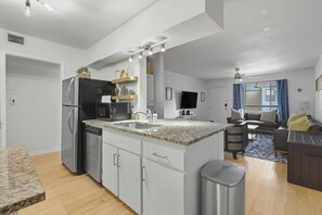 A modern kitchen with a granite countertop, stainless steel appliances, and a built-in dishwasher. - Gated Austin 2BR Condo+ Pool - Near South Congress (Austin)