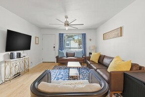 A living room with a flat-screen TV, a ceiling fan, a sofa set, a coffee table, and a patterned rug. - Gated Austin 2BR Condo+ Pool - Near South Congress (Austin)
