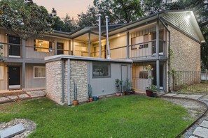A two-story building with a stone facade, multiple balconies, and a well-maintained lawn. - Gated Austin 2BR Condo+ Pool - Near South Congress (Austin)