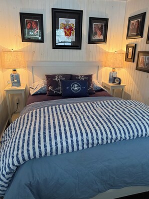 A bedroom with a bed, two nightstands, a lamp, and framed pictures on the wall. - COZY 1-bedroom Charming Cottage located in Midcoast Maine 15 minutes from Camden (Appleton)