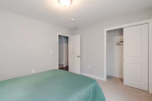 Quarto com cama, armário e porta que dá para outro cômodo.