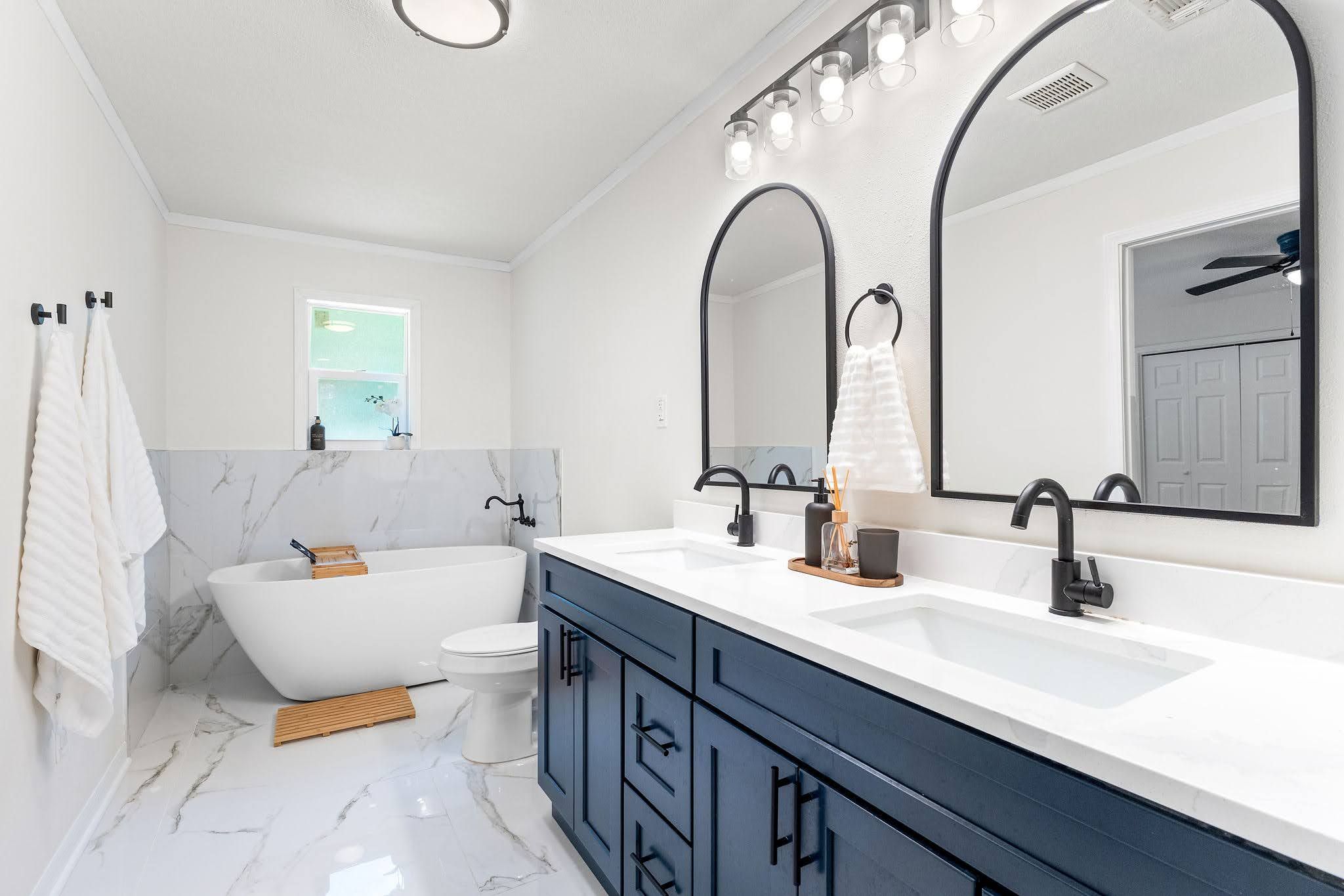 Une salle de bain moderne avec une baignoire sur pieds, un meuble-lavabo à deux vasques et un grand miroir au-dessus du meuble.