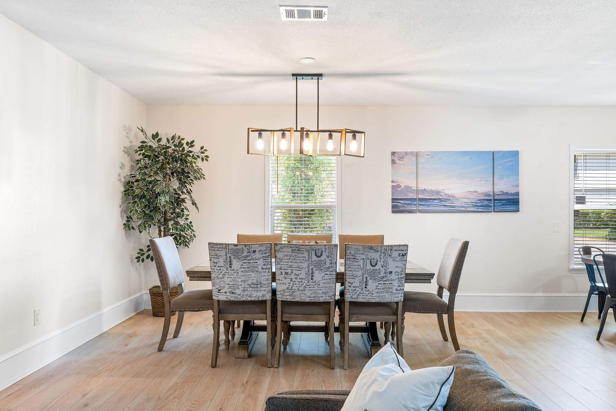 A dining area with a wooden table, chairs, and a hanging light fixture.