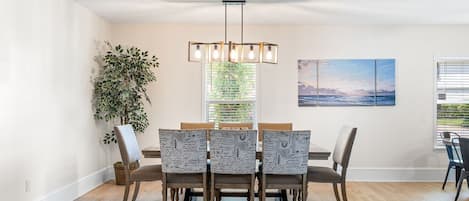 Een eetruimte met een houten tafel, stoelen en een hanglamp.