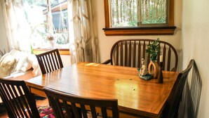 Un tavolo da pranzo in legno con sei sedie, una pianta decorativa e una finestra con tende a macramè.