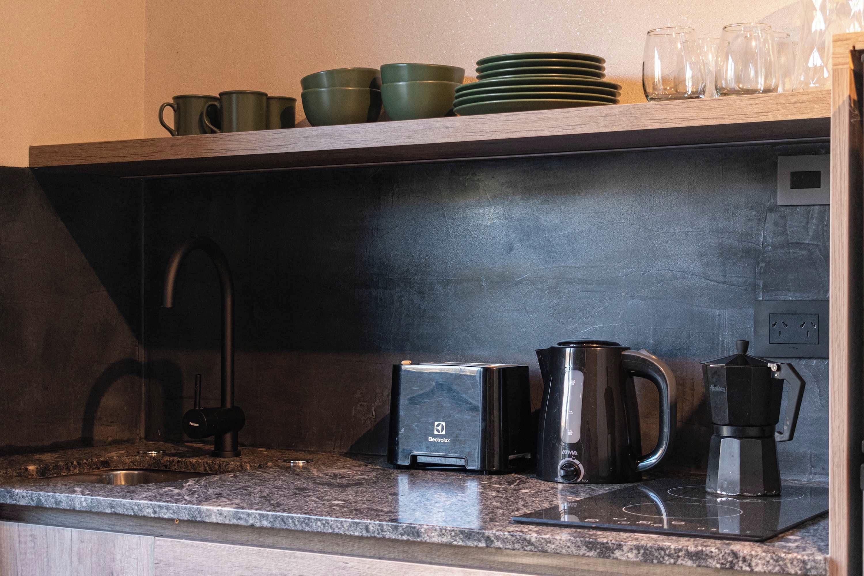 A kitchen with a black countertop, a coffee maker, a kettle, and a toaster.