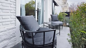 An outdoor seating area with a modern design, featuring a table and two chairs with grey cushions. - MOT Rentals River Plate Loft 1 - 100m to Stadium (Buenos Aires)