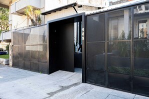 A modern building facade with a large glass door and a metal mesh screen.