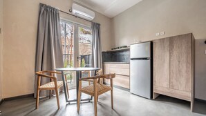 A compact kitchen with a refrigerator, a dining table with chairs, and a window with curtains. - MOT Rentals River Plate Loft 1 - 100m to Stadium (Buenos Aires)