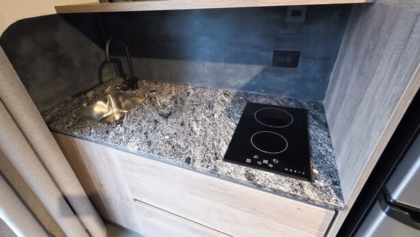 A kitchen with a granite countertop, a black induction cooktop, and a stainless steel refrigerator. - MOT Rentals River Plate Loft 1 - 100m to Stadium (Buenos Aires)