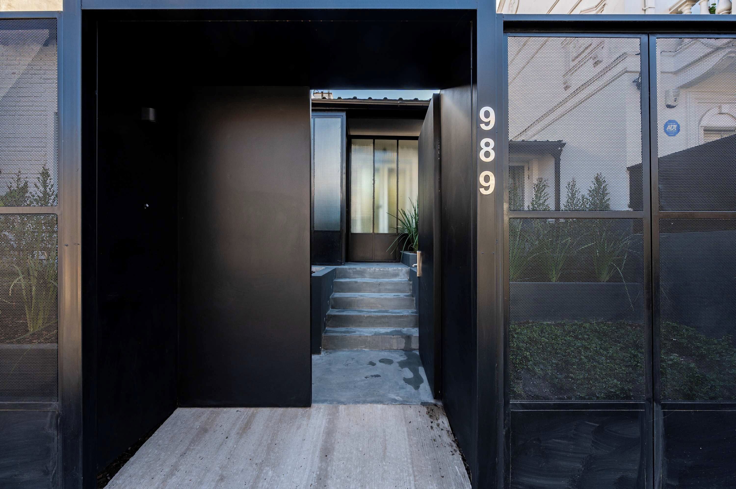 A modern building entrance with a staircase leading to a door marked with the number 989.