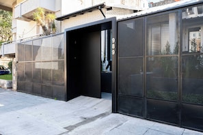 Fachada de edificio moderno con puerta de vidrio grande y celosía metálica.