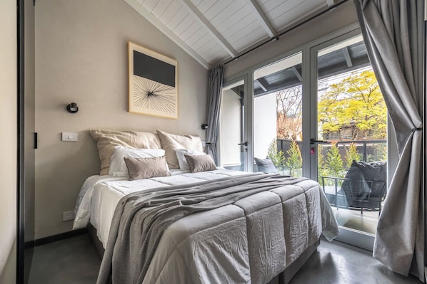 A bedroom with a bed, a window, and a view of the outdoors.