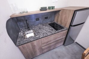 A compact kitchen with a granite countertop, a toaster, a built-in stove, and a refrigerator.