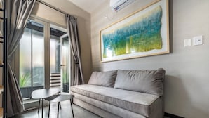 Ein modernes Wohnzimmer mit einem grauen Sofa, einem kleinen Tisch und einem großen abstrakten Gemälde an der Wand.