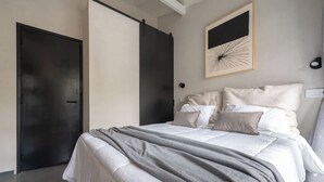 Ein Schlafzimmer mit einem Bett, Kissen, einer Decke, einem Wandbild und einer Tür.