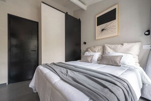 Ein Schlafzimmer mit einem Bett, Kissen, einer Decke, einem Wandbild und einer Tür.