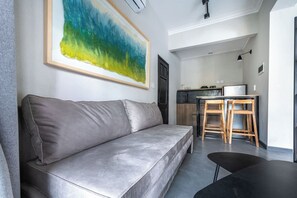 Ein modernes Wohnzimmer mit einem grauen Sofa, einem schwarzen Couchtisch und einem großen abstrakten Gemälde an der Wand.