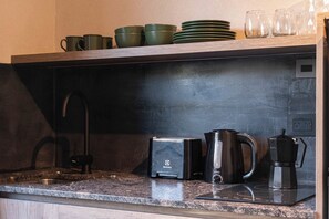 A kitchen with a black countertop, a coffee maker, a kettle, and a toaster. - MOT Rentals + River Plate 2 Lux Lofts A - 100m to Stadium (Buenos Aires)
