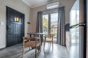 A room with a black door, a round table with two chairs, a window with curtains, and a refrigerator. - MOT Rentals + River Plate 2 Lux Lofts A - 100m to Stadium (Buenos Aires)