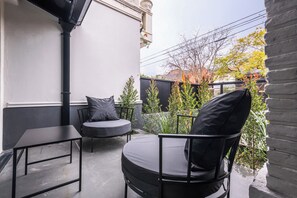 A patio with a table and two chairs, a black grill, and a view of a garden with trees and a fence. - MOT Rentals + River Plate 2 Lux Lofts A - 100m to Stadium (Buenos Aires)