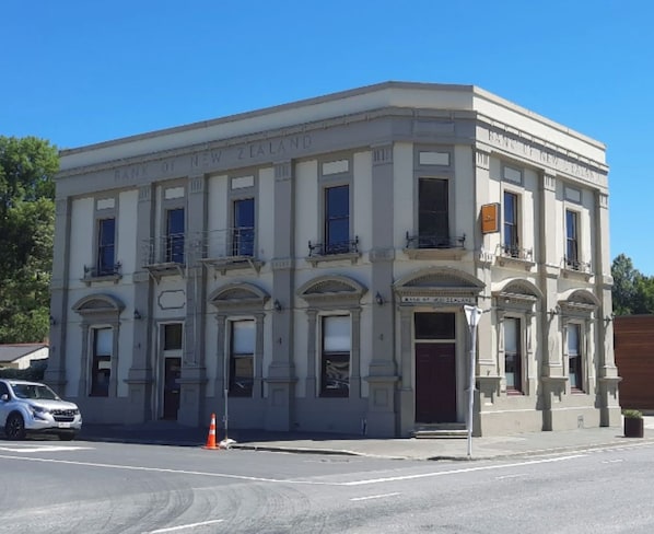 Um edifício histórico com arquitetura clássica, apresentando fachada simétrica, grandes janelas e elementos decorativos.