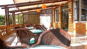 En uteplats med flätade möbler och bord av glas, en pergola av trä och utsikt över det omgivande området.