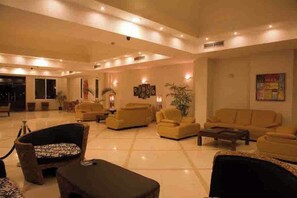 A spacious lobby with multiple seating areas, a reception desk, and a large window. - Siesta Marina Hotel (Al-Hammam)