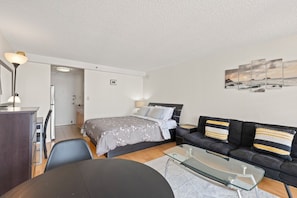 Ein modernes Schlafzimmer mit Bett, Sofa, Glastisch und Schreibtisch.