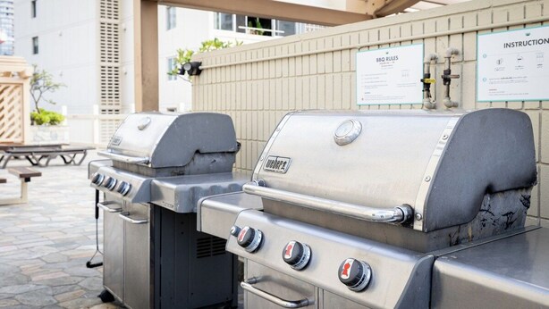 A barbecue grill area with instructions and rules posted on the wall. - Cozy 1-bedroom condo with AC in Waikiki (Honolulu)