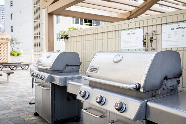 A barbecue grill area with instructions and rules posted on the wall. - Cozy 1-bedroom condo with AC in Waikiki (Honolulu)
