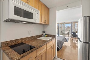 A kitchen with granite countertops, a microwave, and a sink. - Cozy 1-bedroom condo with AC in Waikiki (Honolulu)