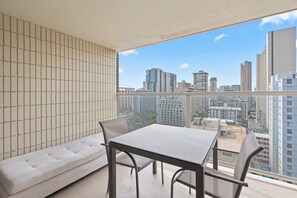 A balcony with a city view, a sofa, and a table with chairs. - Cozy 1-bedroom condo with AC in Waikiki (Honolulu)