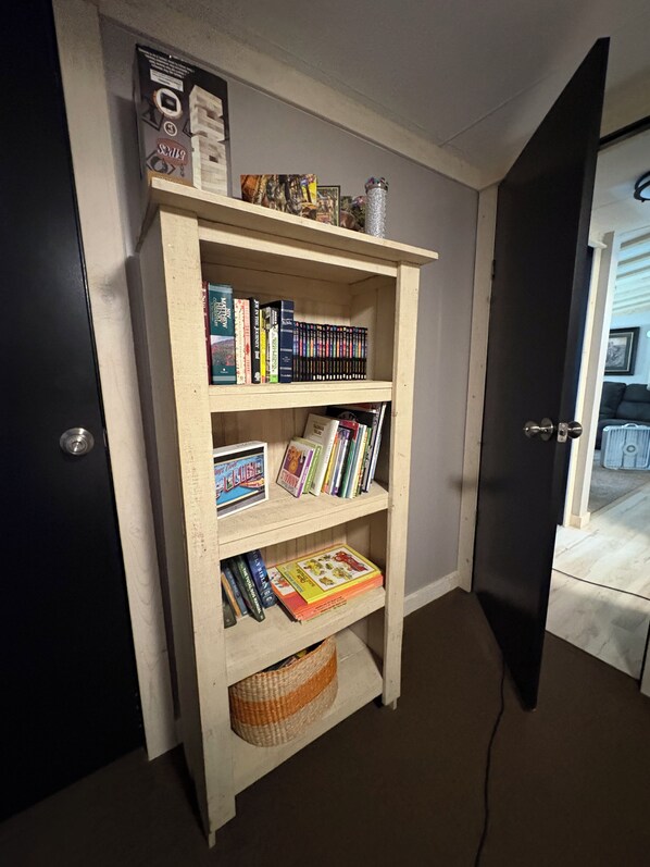 A bookshelf with various books and a small decorative item on top.