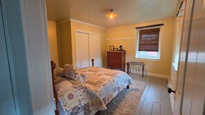 A bedroom with a bed, dresser, window, and a door.