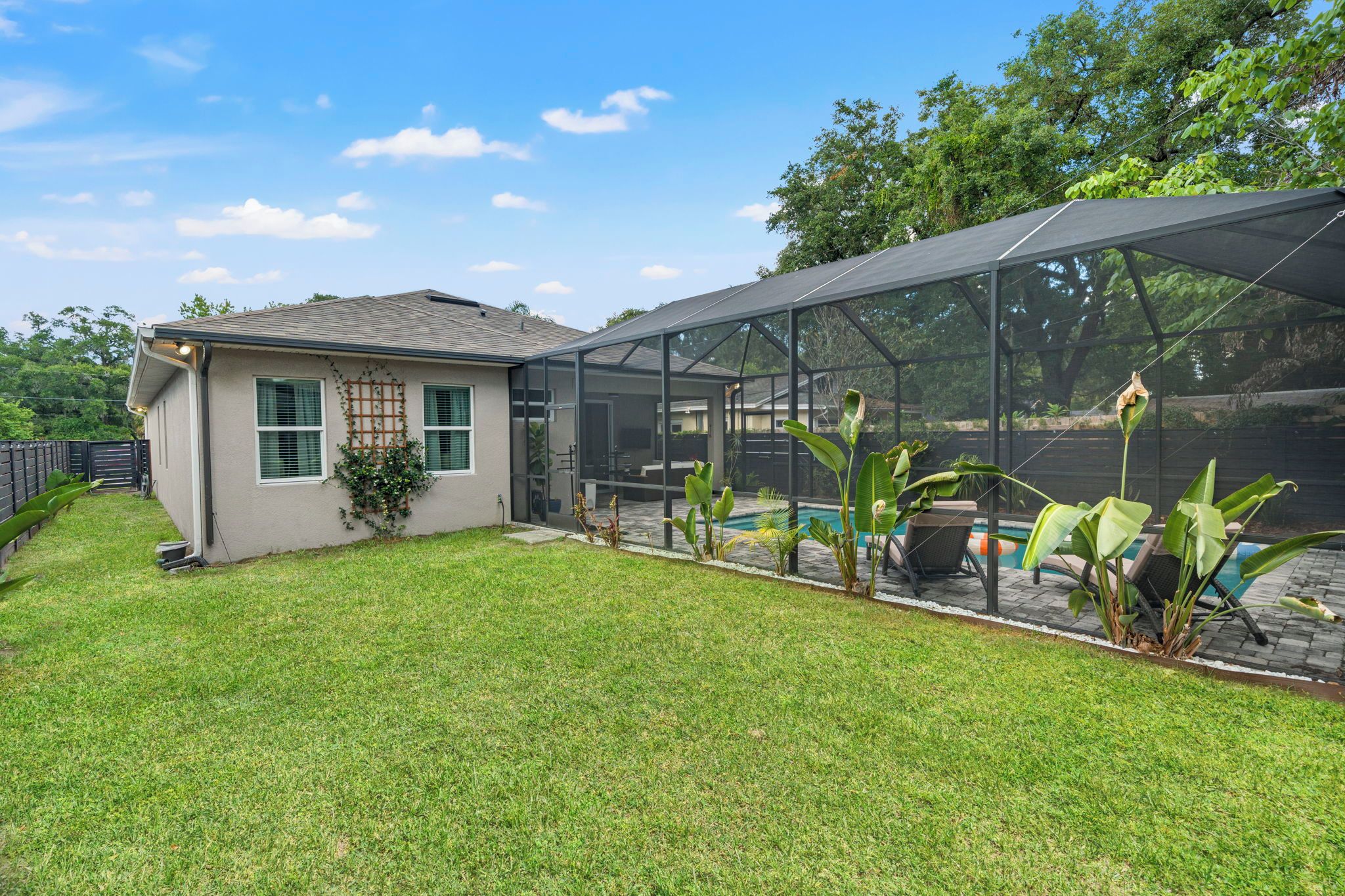 A house with a screened porch, a swimming pool, and a well-maintained lawn.