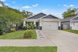 A two-story house with a garage, number 1507, surrounded by a well-maintained lawn and a wooden fence. - Heated Pool Getaway In Tampa Bay, Sleeps, Close to everything in Tampa Bay! (Tampa)