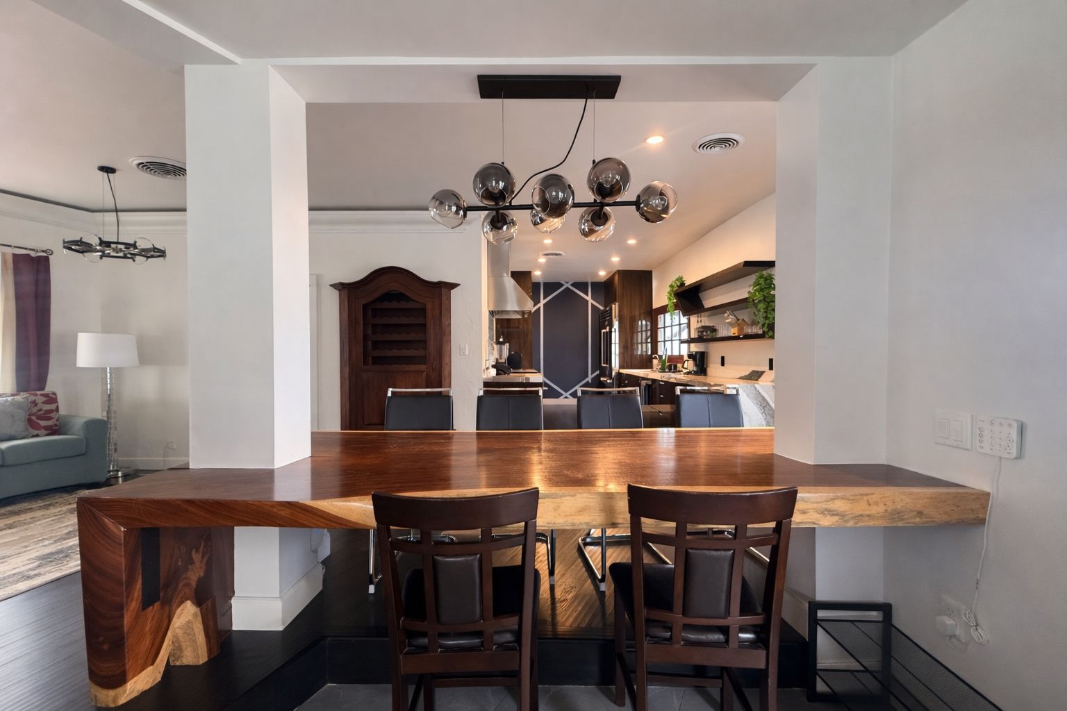 Cozinha moderna com ilha central, piso em madeira escura e lustre.