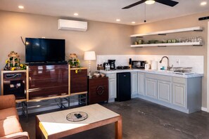 A modern kitchen with a built-in oven, microwave, and coffee maker. There is a dining area with a table and chairs, and a flat-screen TV mounted on the wall. - Private Villa w/ Pool, Spa, Gym, Sauna, Spectacular Backyard, & 2 miles to Strip (Las Vegas)