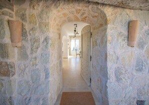 A stone-walled hallway leading to a room with a door, a hanging light fixture, and a view into another room. - Cabris, Mas provençal 6p, 3ch, AC, piscine, vue (Cabris)