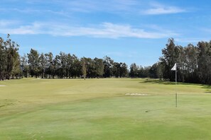 A golf course with a flagstick, trees, and a clear sky. - Duck Pond Villa at Hunter Valley Golf Resort Views (Lovedale)