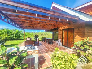 A covered patio with outdoor furniture, a grill, and a view of the surrounding greenery. - Beautiful 3-bedroomChalet, perfer or families and privacy, 5min in car from twon (San Carlos)