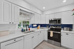 Eine moderne Küche mit weißen Schränken, Edelstahlgeräten und einer blauen Spritzschutzwand.