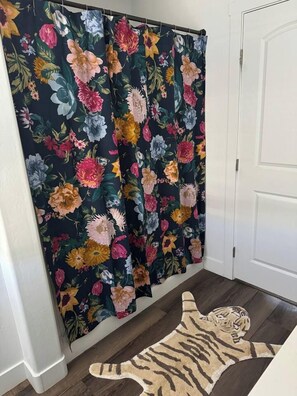 Ein Zimmer mit einem blumigen Vorhang, einem Tigerstreifen-Teppich und einer weißen Tür.