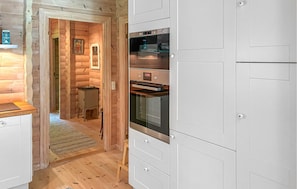 Una cocina compacta con horno integrado, un mueble pequeño y suelo de madera.