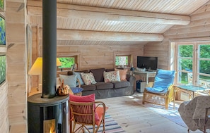 Un interior de cabaña acogedor con chimenea, un sofá y sillones de mimbre.